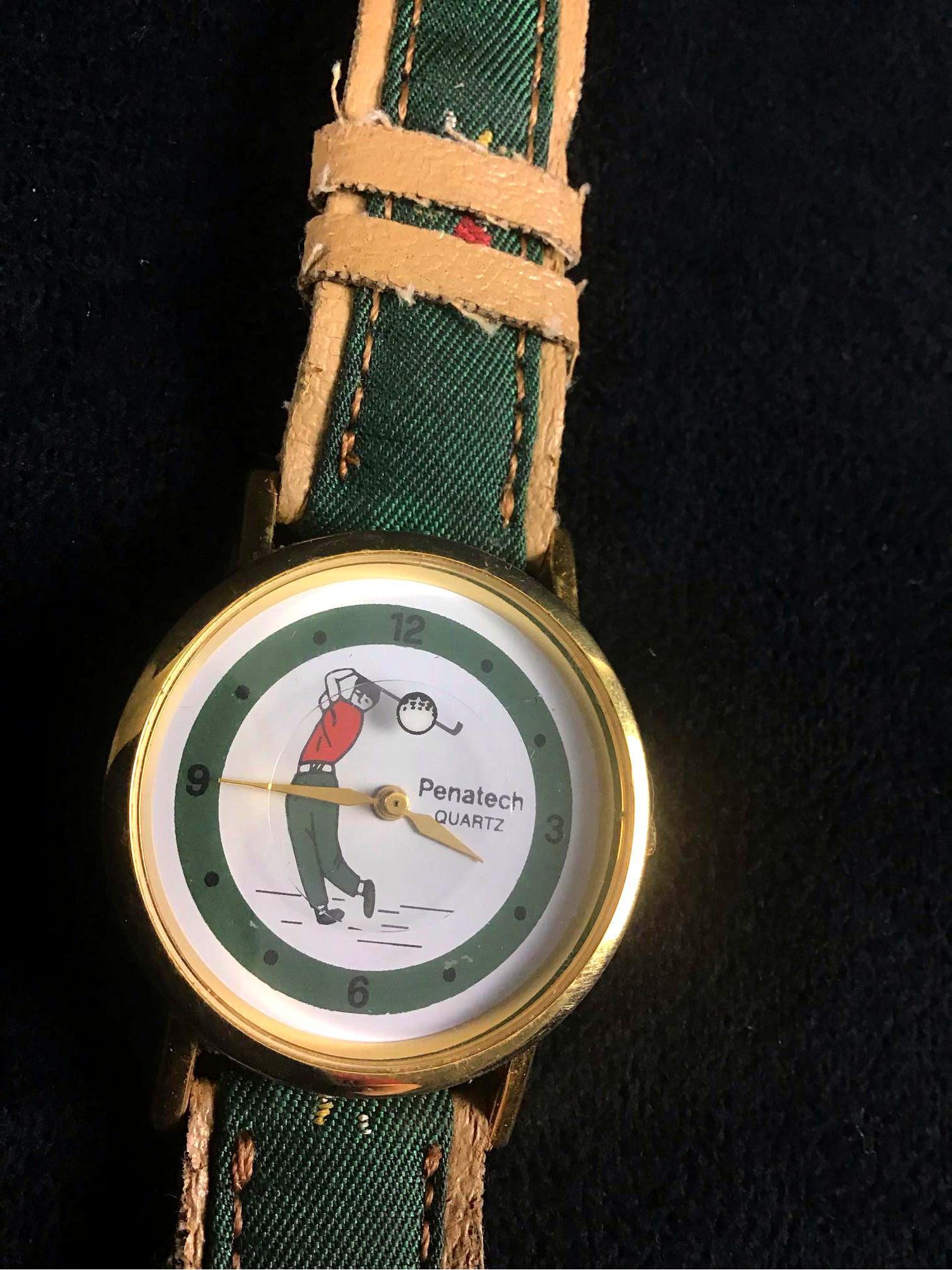 Penatech Quartz Golf Embroidered watch: This is a Penatech quartz golf watch. It is green and brown. The bezel, crown, and clasp are gold colored. The straps have embroidered golfers featured. The back of the watch says "stainless steel bac
