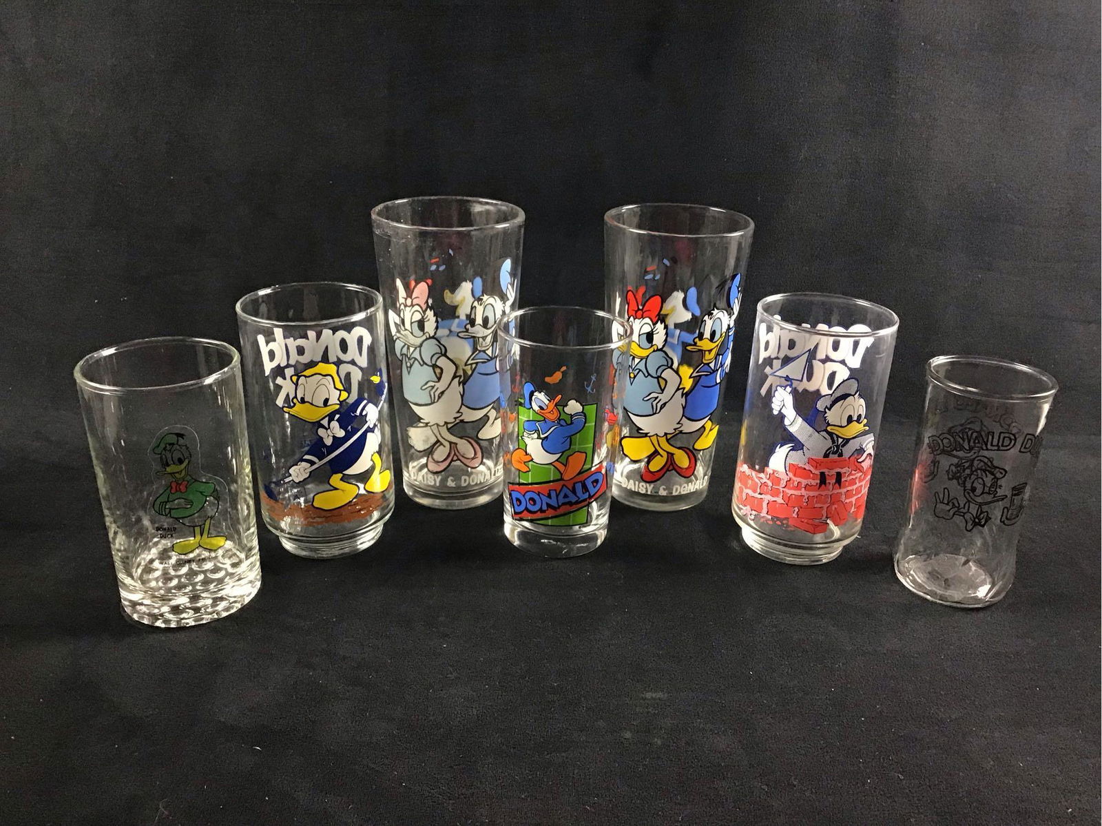 Lot of 7 Donald Duck Daisy Vintage Glass Cups: These glass cups appear vintage due to its unique art style and design. This lot would make a great addition to Disney or Donald Duck collectors. They are in general good condition. Some have known sc