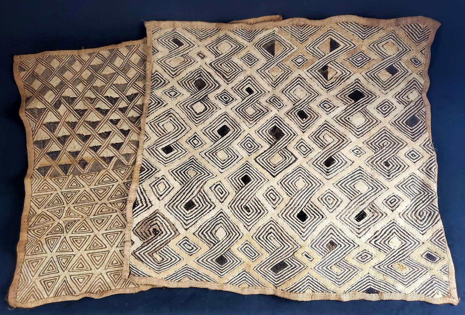 2 Antique African Kuba Woven Artisan Mats B: This lot of two African Kuba artisan woven mats/rugs are from the mid to late 1800s. The unique textile pattern displays diamond and triangular shapes with a play on contrast. Not perfectly square. Th