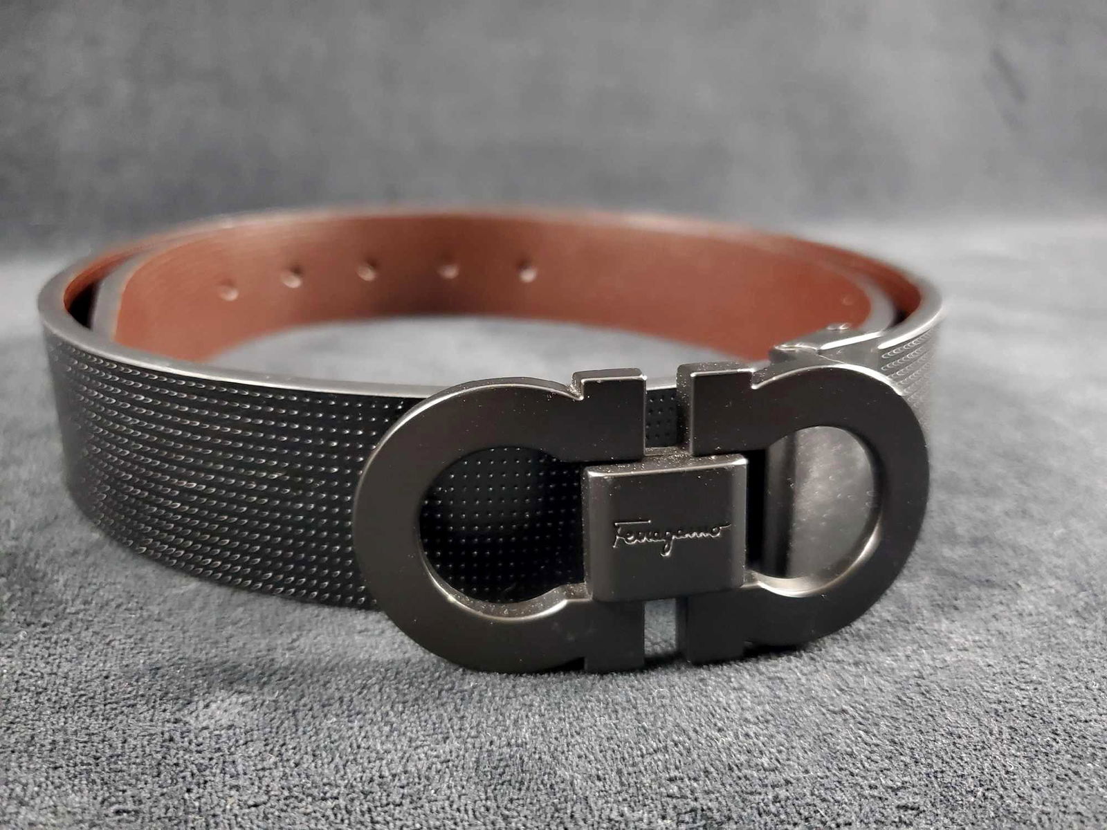 Salvatore Ferragamo Reversible Calf Belt W Gancini: Salvatore Ferragamo Reversible Calf Belt With Gancini Buckle. This reversible belt has black perforated leather on one side and brown perforated on the other. The gancini buckle is a matte black and m