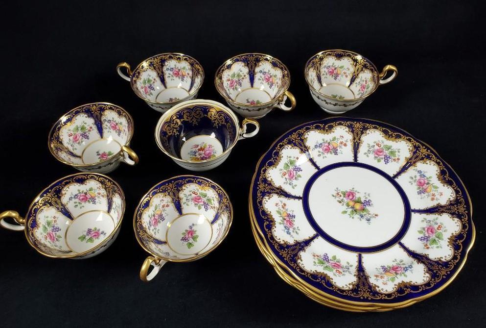 Aynsley England Bone China: This lot of Ansley England Bone china consists of 7 tea cups and 5 salad plates. The set depicts a lovely royal blue with fruit and floral pressed design and gold accents. Marked Ansley Engl
