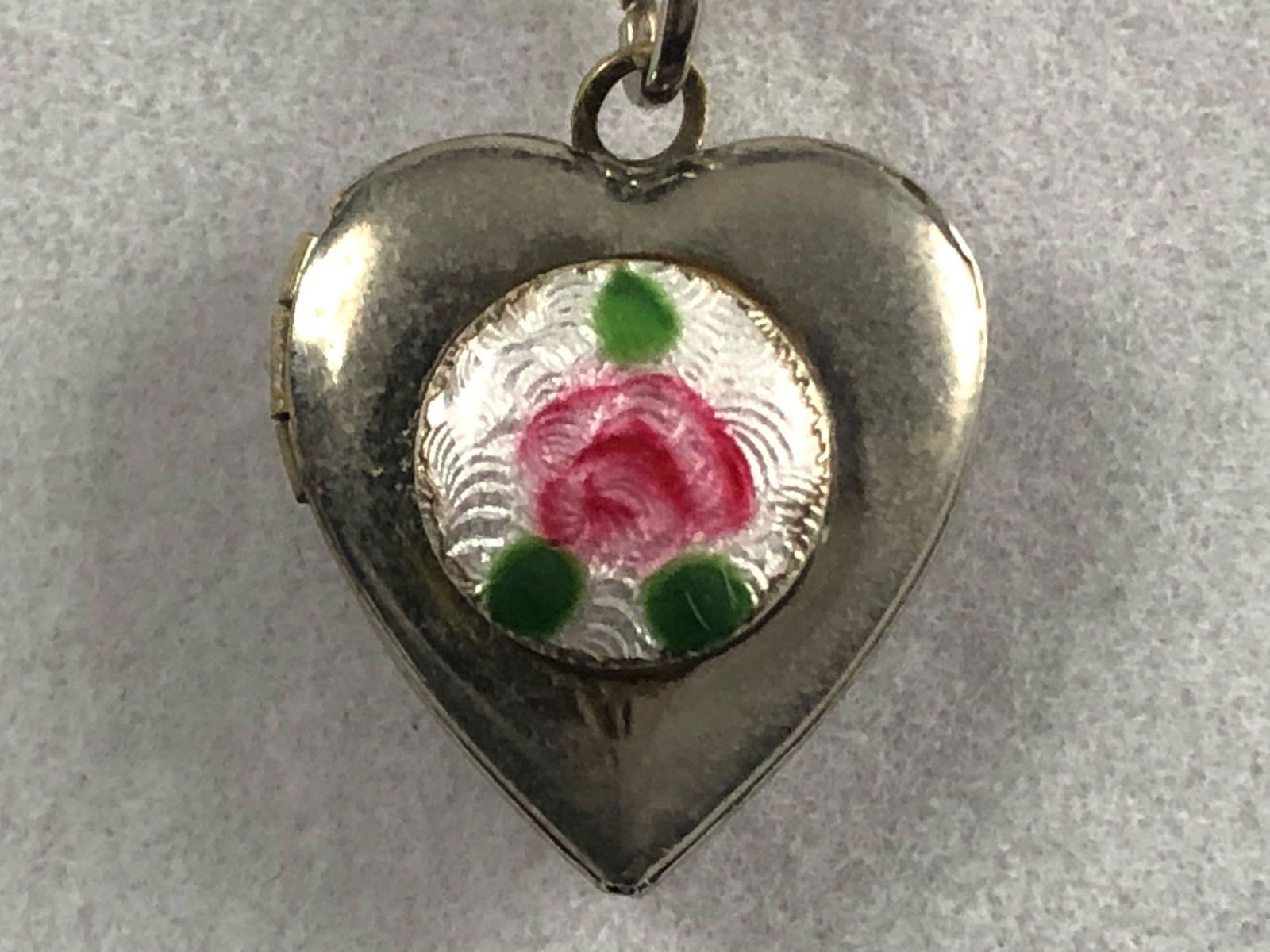 Antique Guilloche Enamel Heart Locket & Sterling 18": Antique guilloche flower enamel heart locket & sterling silver chain. The Italian antique design silver plated locket is in good condition with light scuffs, tarnishing and patina. The chain measures