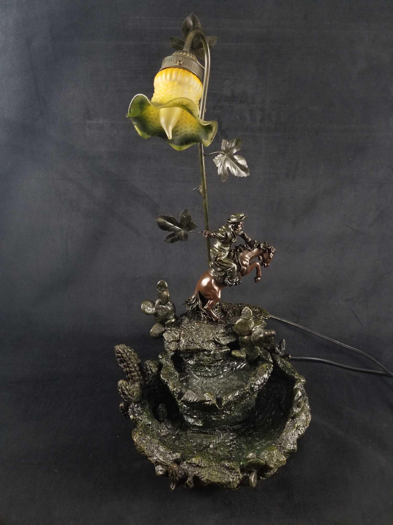 Bronze Western Cowboy Sculpture Light and Fountain: Hand painted Bronze Western Cowboy rock water feature with light. This sculpture depicts a western cowboy on a horse in mid gallop on top of rocks with cactus and a vintage green flower light. Unfortu