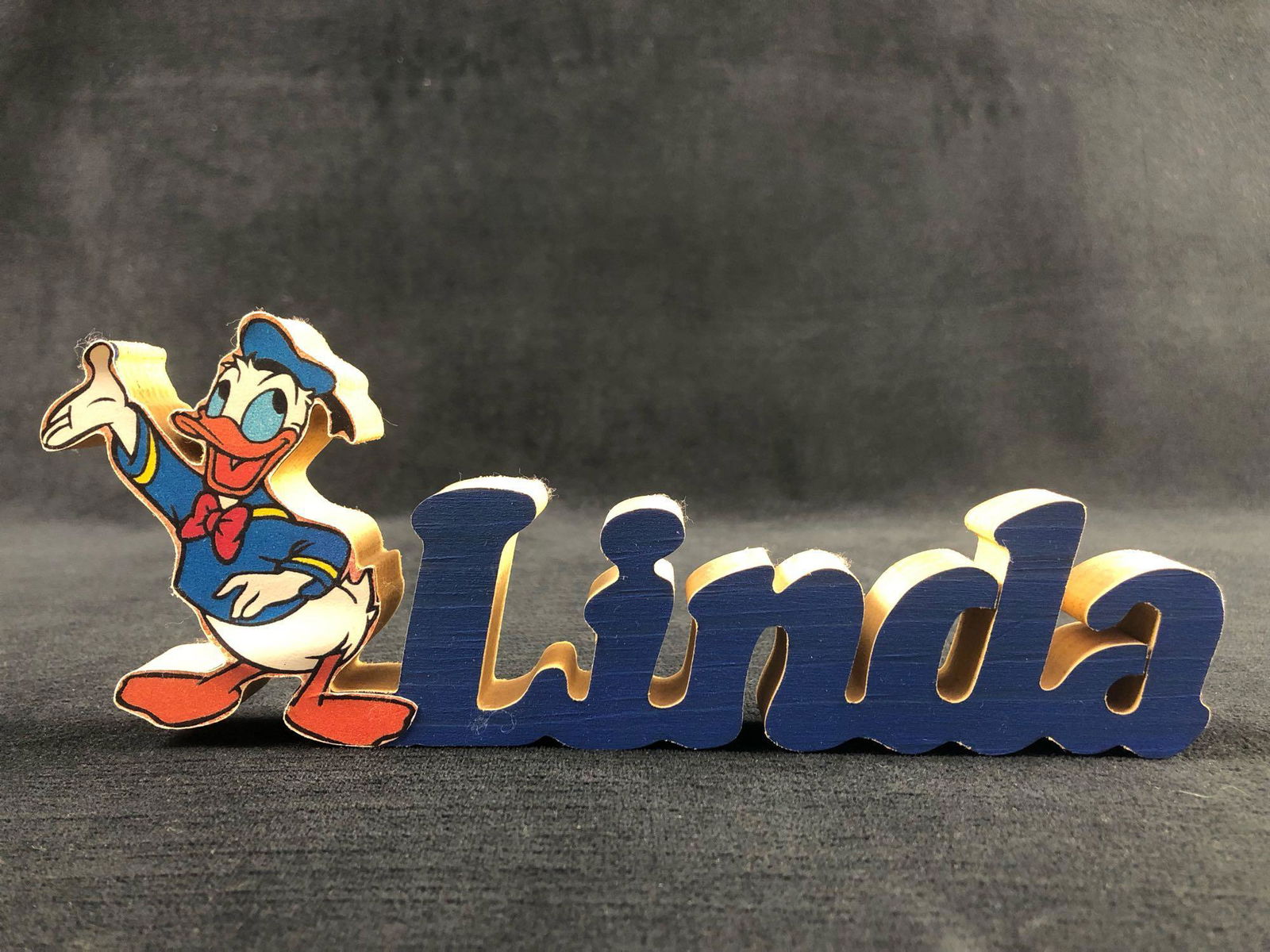 Donald Duck Wooden name "LINDA" Carving Sign: Donald Duck Wooden name "LINDA" Carving Sign Â A special Donald Duck sign for LINDA! A crafted item made out of wood and painted blue on the blue lettering. Donald Duck standing tall in his classic