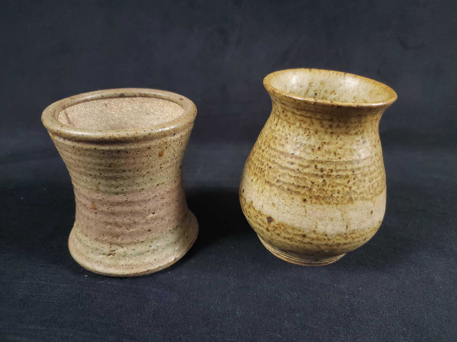 Vintage Hand Made Earthenware Cups Lot Of Two: This lot includes two earthenware mugs/vases. The larger of the mugs has the name "Rudy" etched on the bottom. Both are in good, vintage condition with the larger have a slight chip on the top of the 