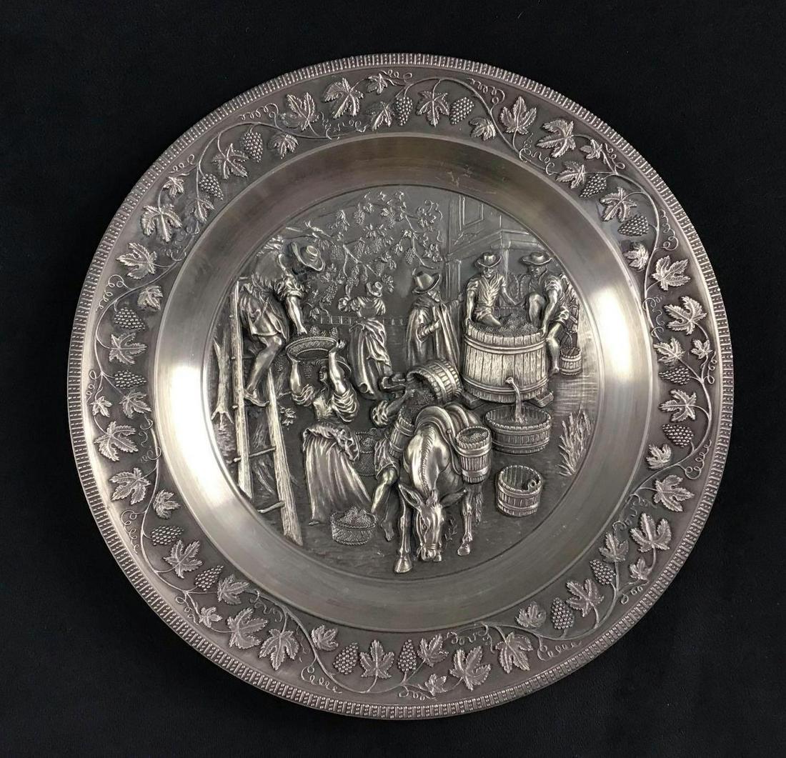 German Pewter Old World Wine Making Scene Plate Vintage: This is a German made pewter plate circa 1900s. It depicts old world wine making. It has a high raised relief that brings out a lot of detail in the design. There is a hanger in the back for display p