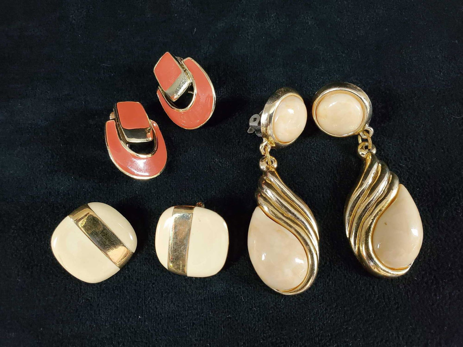 Vintage 1970s Clip On Earring Lot of 3: This 3 piece lot consists of: (1) A pair of coral colored clip on earring with gold toned backing. Measures approx 1" x 3/4". In good condition with some scuffs. (1) Square shaped cream and gold tone 