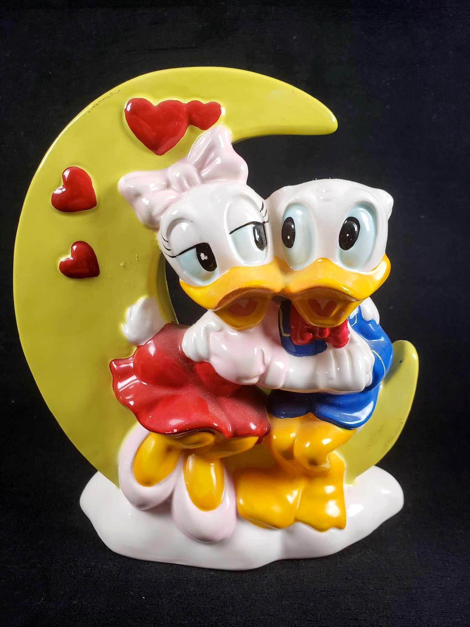 Donald and Daisy Duck Moon Porcelain Vase: Donald and Daisy Duck Moon Porcelain Vase. This Donald and Daisy Duck vase is in good used condition. The vase shows some minor signs of wear such as areas of paint loss and residue/dust on some areas