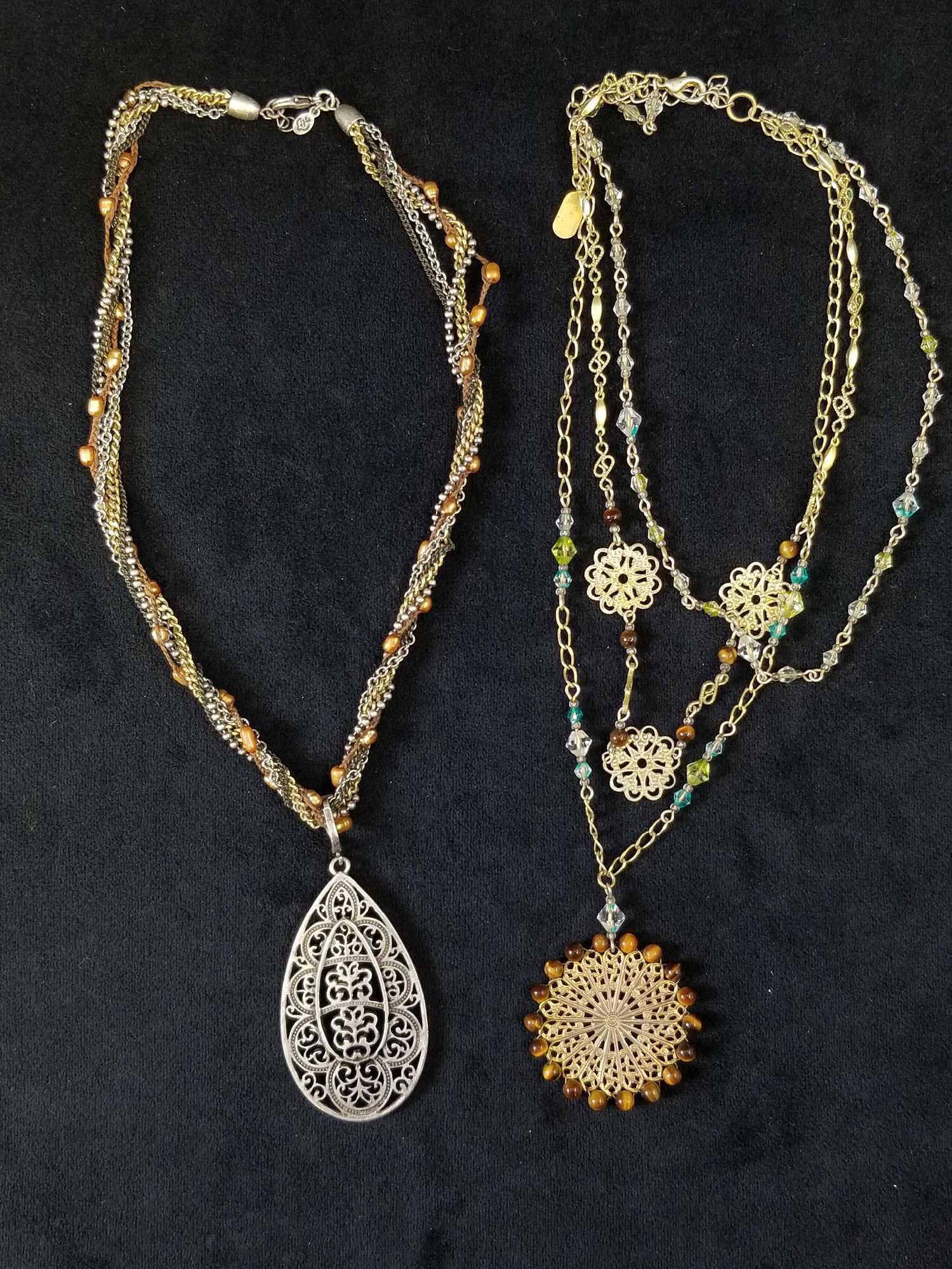 Lot of 2 Vintage Style Necklaces With Medallion: This lot of 2 necklaces both consist of 17" length chains. One has gold, silver, black tone chain link necklaces with brown braided string with honey colored beads intertwined with one another. The me