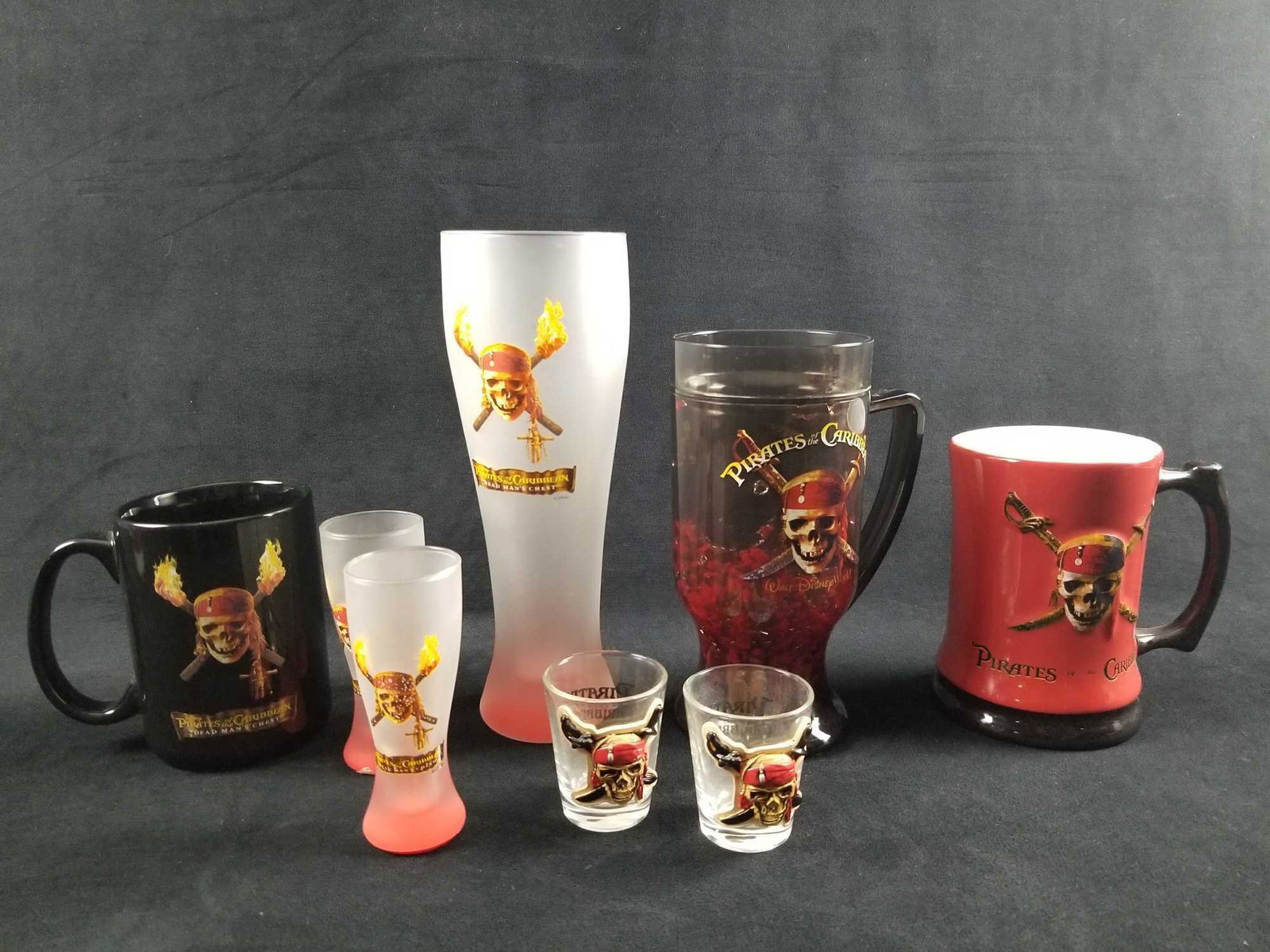 Lot of 8 Pirates of the Caribbean Modern Drinkware: This is a variety of different drinkwares. These are in good condition with some known scuffs. In total this lot consists of the following; (1) 2 Shot glasses. these feature 3-D skulls on them. Approx