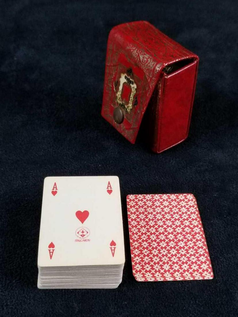 Fiocchi Italy Minature Cards In Leather Case: Fiocchi Italy miniature playing cards come in a red, hard leather, snap case. The case has a gold, black, and green gilt design. The interior snap is labeled Fiocchi Italy. All 52 cards are in the dec