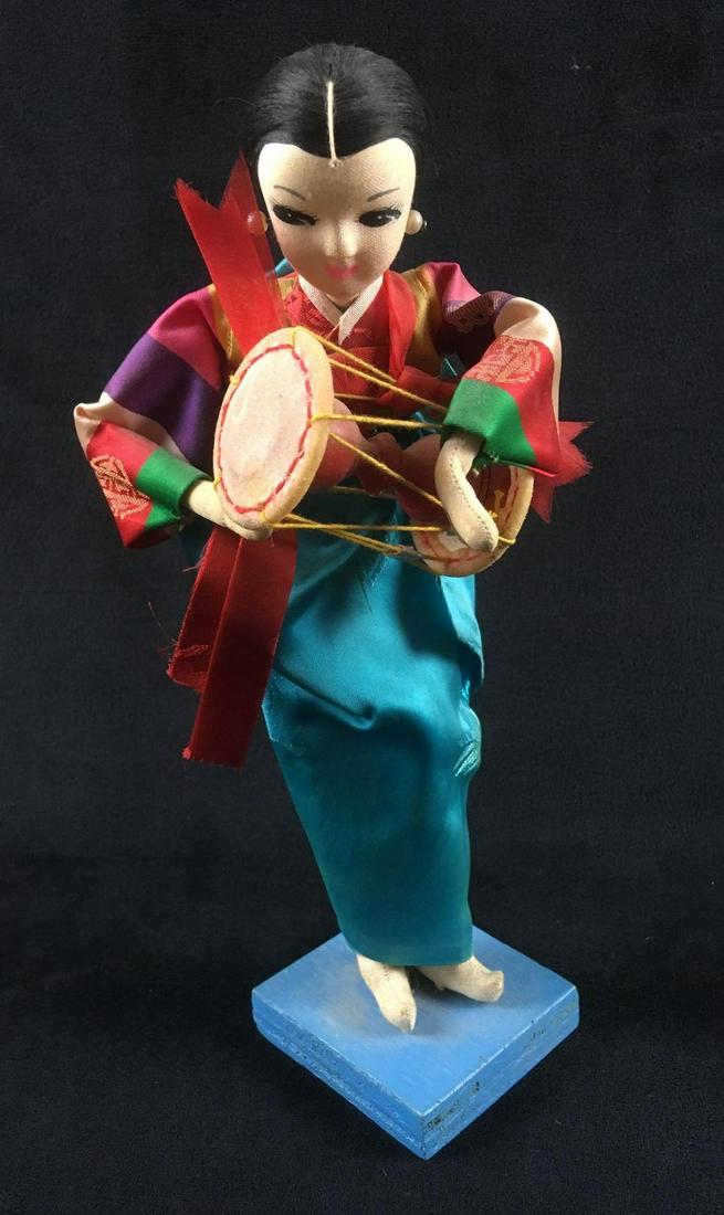 Doll in Traditional Korean Dress: Doll in Traditional Korean Dress. This doll is in fair condition. Doll is holding a traditional Korean instrument. Some dust on the doll. Body is made of fabric and wire. Doll measures 9" H and stands
