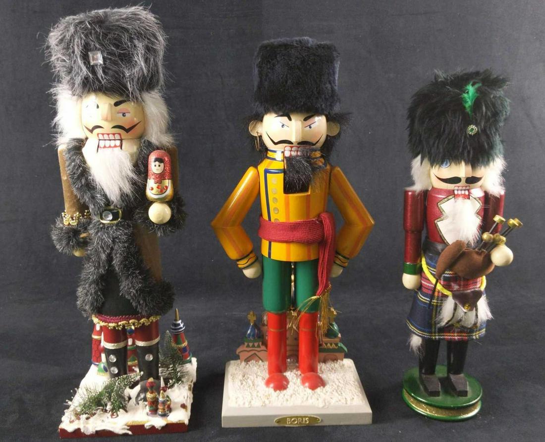 Three Russian And Scotsman Wooden Nutcrackers Christmas: This lot includes: (1) Wooden Scotsman With Kilt And Bagpipes Nutcracker. Is approx 3" x 3" x 14". Has a crack (or scar) on the right side of his face. Maker is unknown. (1) Wooden Russian With Nestin