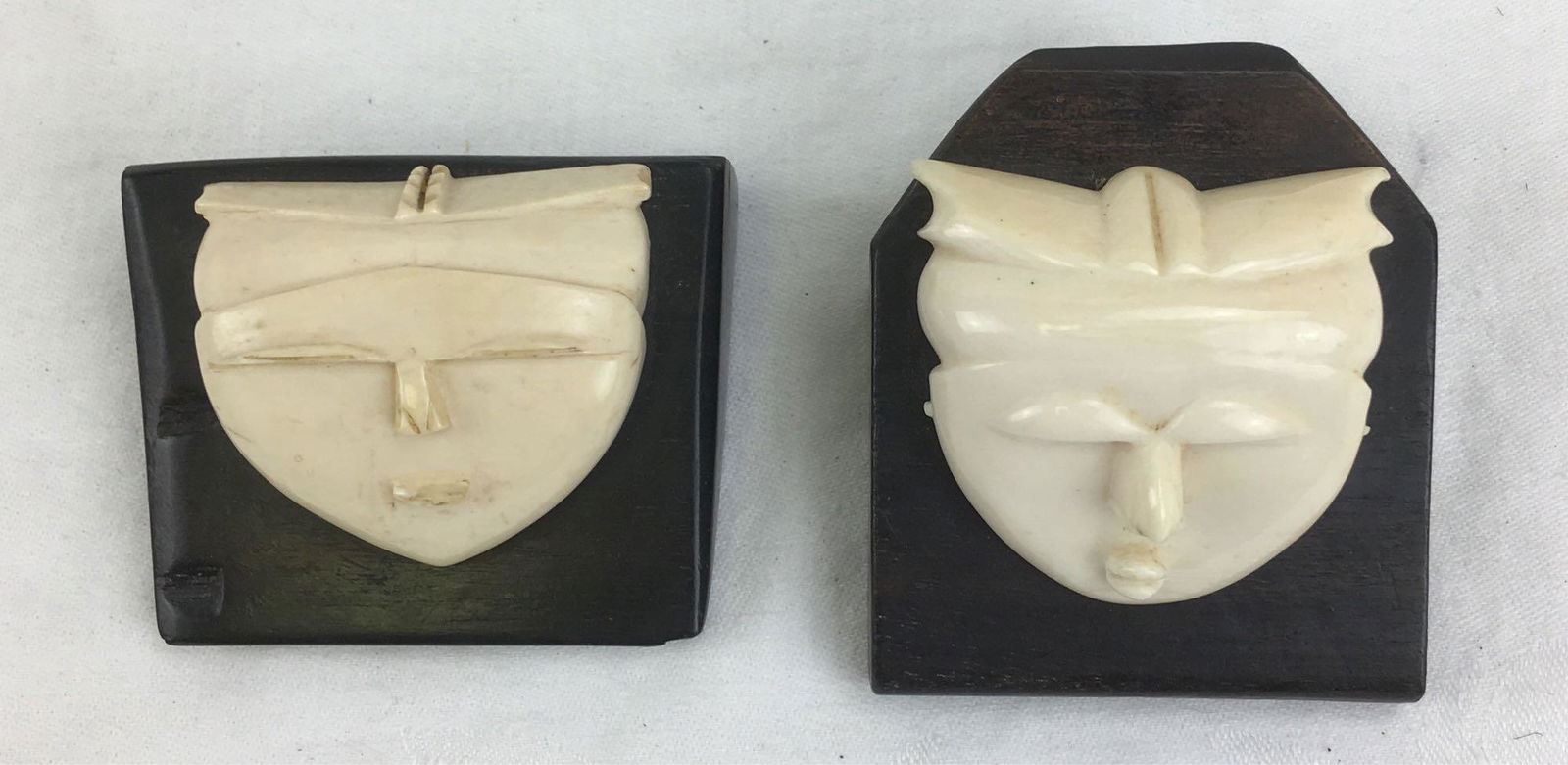 2 Vintage Carved Masks Mounted on Ebony in Japanese: 2 Vintage Carved Masks Mounted on Ebony in Japanese Style; these carved masks are in an ivory-like material. They are mounted on blocks of ebony and show a very stylistic appearance. There are no mark