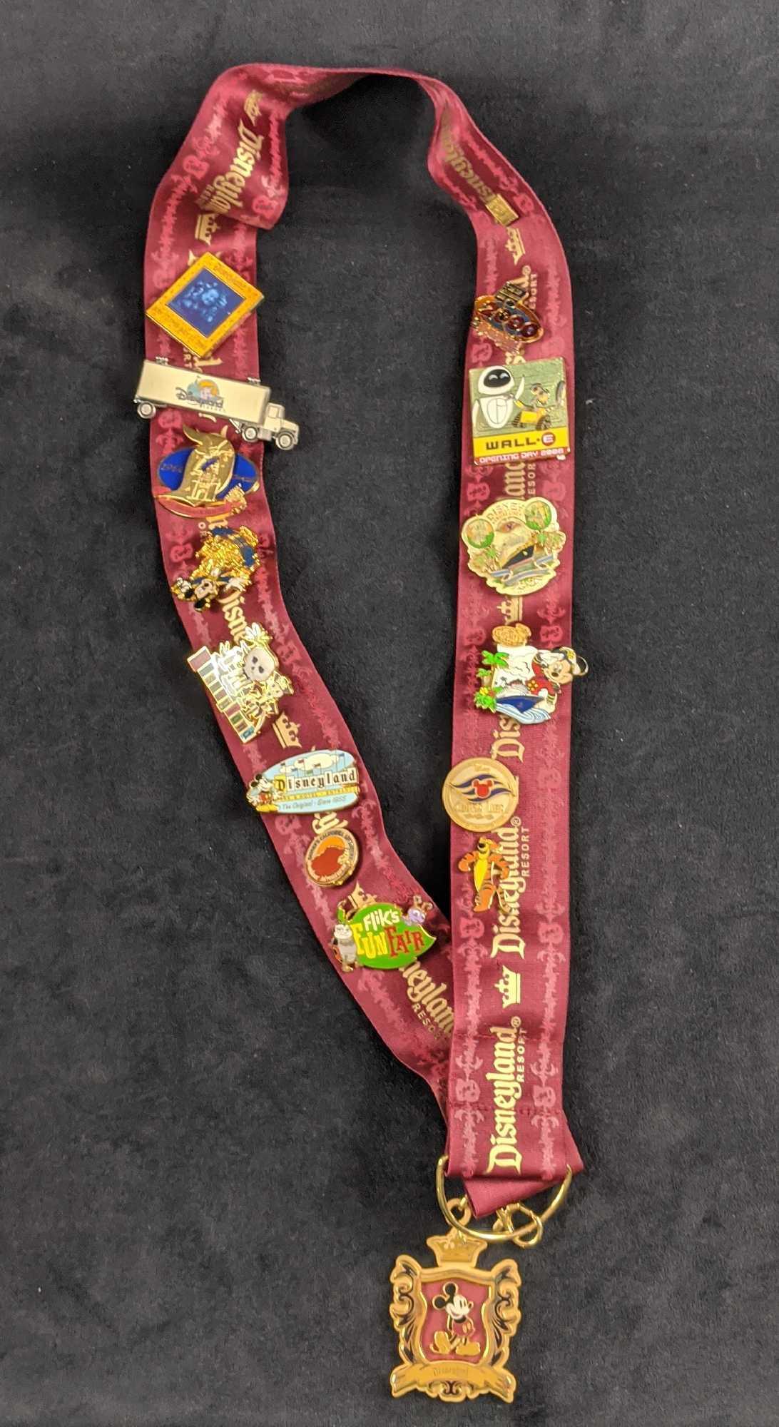 Disneyland Lanyard And Retired Pin Lot Of Fifteen: This lot includes: (1) Disneyland Mickey Mouse Crest Pin Lanyard. (1) Disneyland Flik's Fun Fair Pin. (1) Disney California Adventure Outdoor Adventures Pin (1) Disneyland The Original Since 1955 Pin.