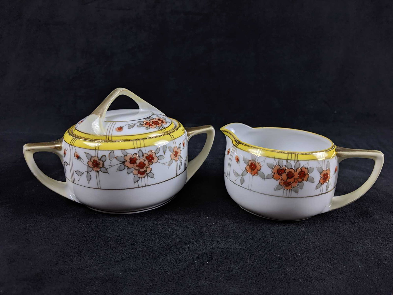 Vintage Noritake Sugar Bowl and Cream Pitcher Set of 2: Vintage Noritake Hand painted Nippon Sugar Bowl and Cream Pitcher Set of 2. 1 Sugar lidded bowl white and yellow with a floral motif and gilded details. There are no known chips or cracks. The gilding