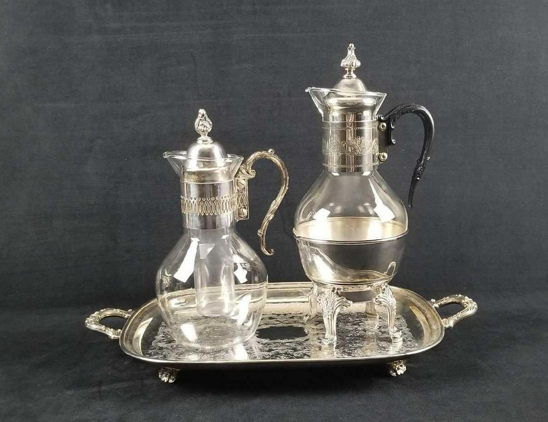 Vintage Silver Plated Tray and 2 Glass Carafes: This silver plated lot contains: 1- Silversmiths "Suffolk" serving tray, footed, with makers marked stamped on bottom. Approx. measures 19" (with handles) x 11" x 1 3/4" 1- Corning glass Coffee/Tea Ca