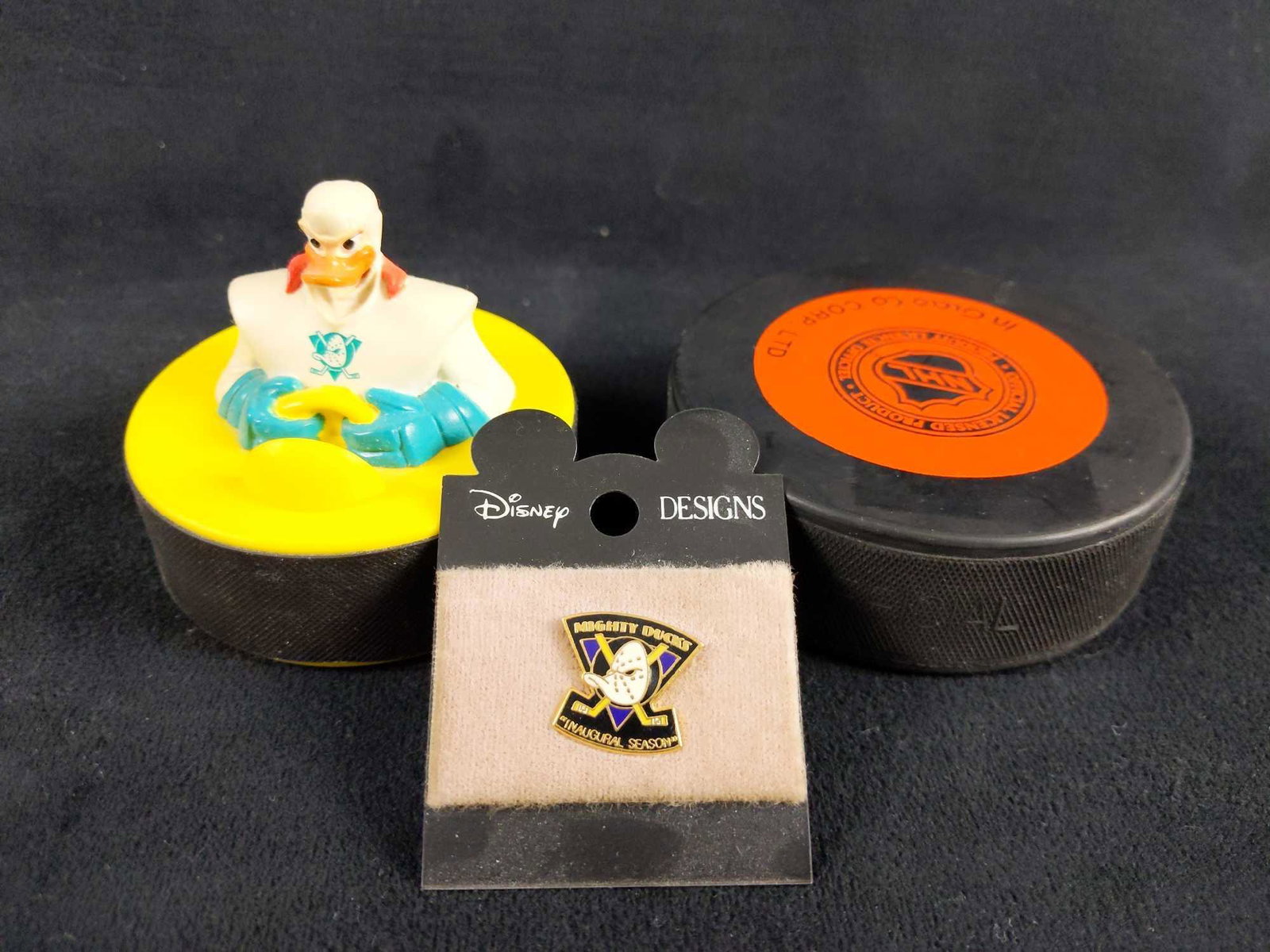 Disney Mighty Ducks Hockey Pucks And Pin Lot Of 3: 1) Mighty Ducks Anaheim Official NHL vintage hockey puck made by Inglasco in Czechoslovakia. Puck is in good condition with no known damages. Measures 3 inches in diameter. 1) Mighty Ducks vintage toy
