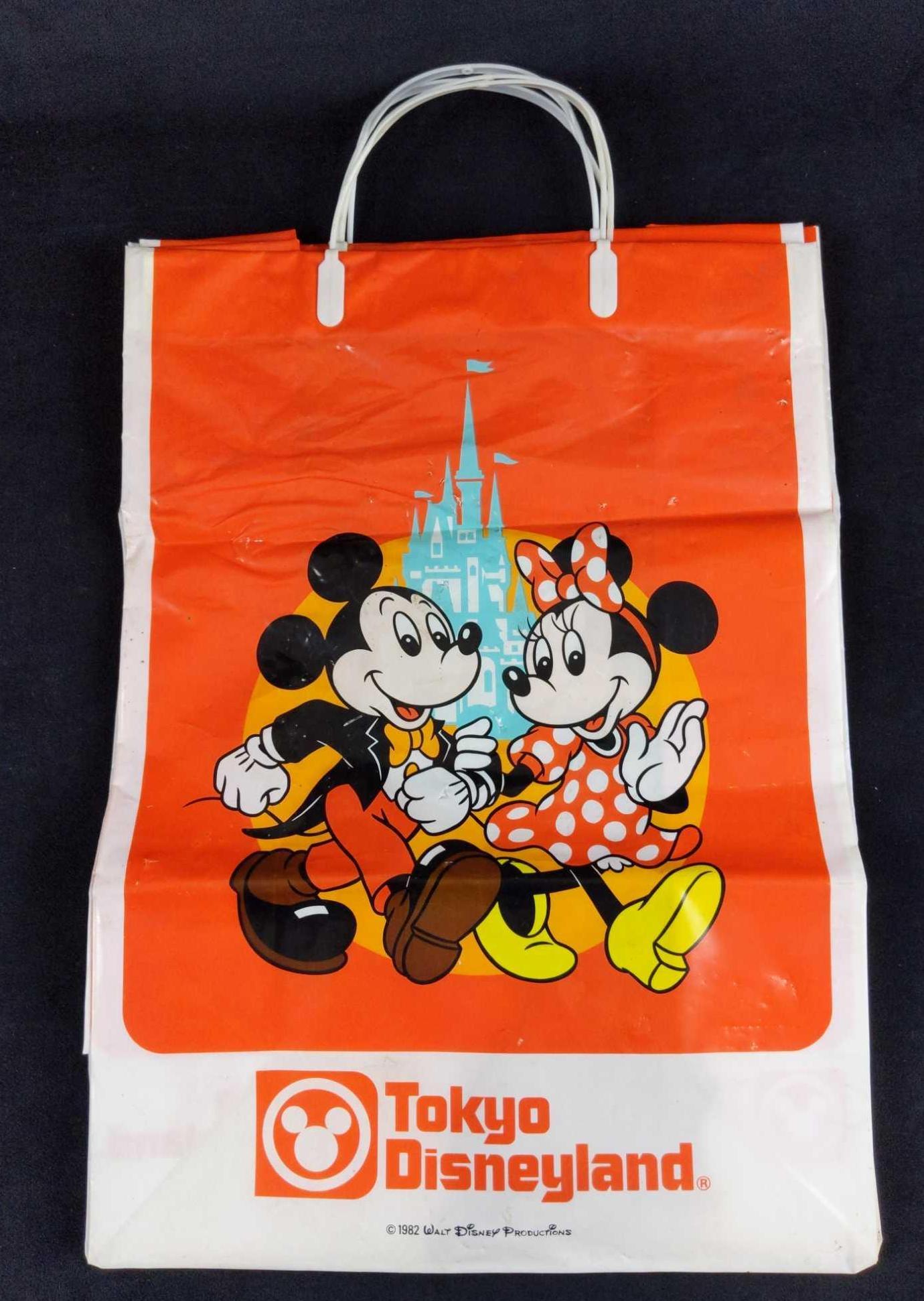 2 Vintage Tokyo Disneyland 1982 Shopping Bags: Two vintage opening day Tokyo Disneyland shopping bags. These bright orange and white plastic shopping bags show a happy Mickey and Minnie Mouse walking by Cinderella's Castle. Bags were made in 1982