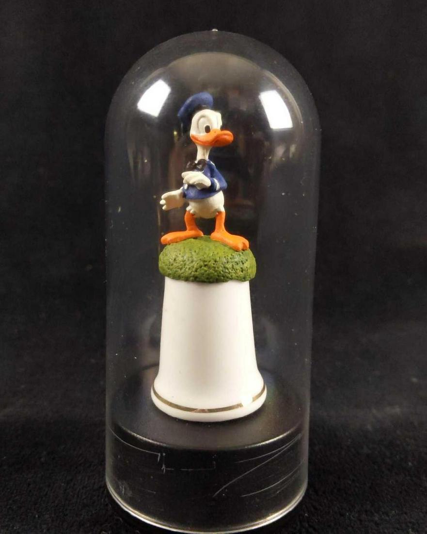 Donald Duck Disney Porcelain Thimble Inside Display: Donald duck figure on porcelain thimble. This thimble was made by Sterling Classic. Great collectible miniature that won't occupy much space. The thimble is secured inside a plastic domed case and is 