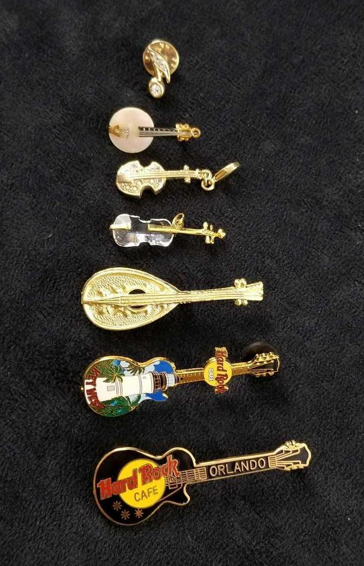Music Pins Lot Of 7: Music pin lot of 7 contains: 2- Hard Rock Cafe from Orlando and Key West 1- Music note pin 2- Instrument pins 1- Cello pendent 1- Instrument charm or keychain accents All clasps are functional and the