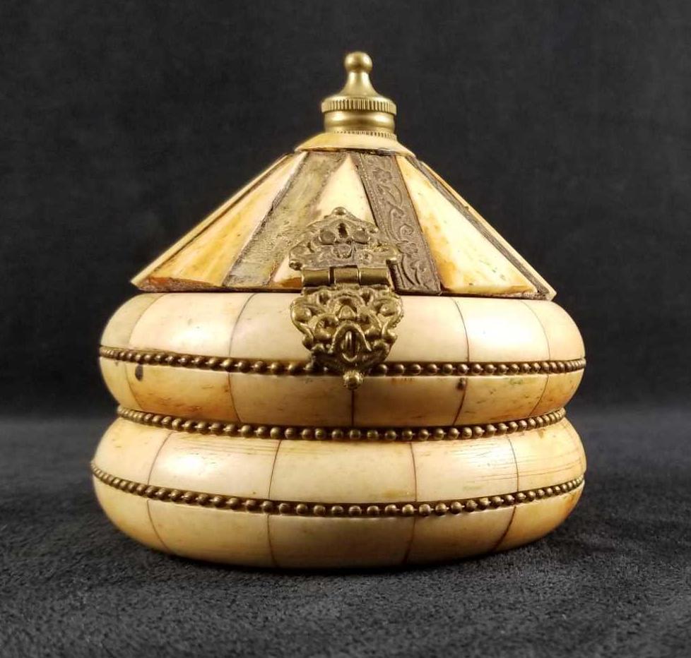 Vintage Camel Bone Brass Middle Eastern Trinket Jewelry: Camel Bone with brass inlay trinket/jewelry box. It is round with a triangular top. Has a middle east design. There is a wood base and purple velvet lining the interior. It is in fair condition with s