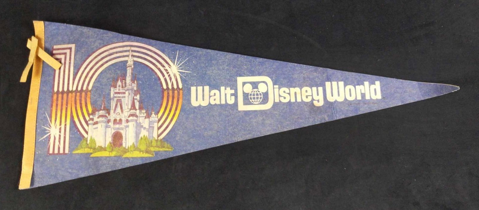 Walt Disney World 10th Anniversary Felt Pennant: A 10th Anniversary blue felt pennant from Walt Disney World. This pennant features castle imagery with the Walt Disney World logo in large white text. Measures 11"x29". In good condition, with some di