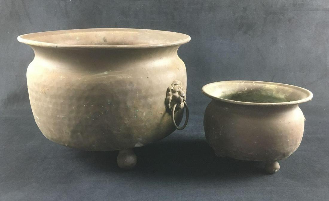 Large Footed Hammered Copper Pot and Small Footed: Large Footed Hammered Copper Pot and Small Footed Copper Pot. These pots are in used condition. Both pots have some signs of oxidation on the surface. The larger pot has lion door knocker type handles