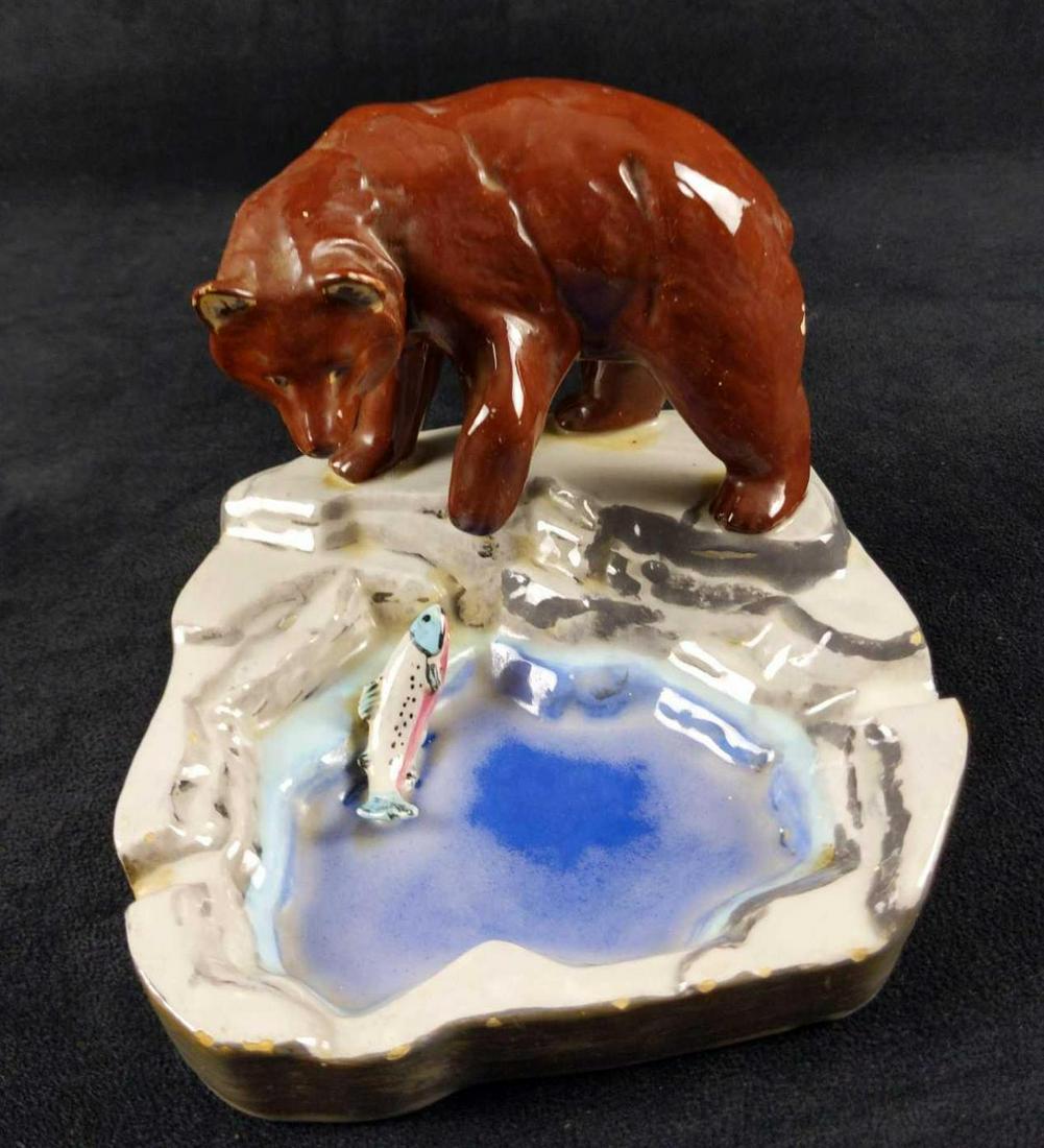 Vintage Bear With Salmon Ceramic Ash Tray: A hungry bear swipes at a pesky salmon on his hand-painted ceramic ashtray. Is signed by an Devoke on the bottom. Ashtray is in good, used condition with some discoloration and a small chip on the bea