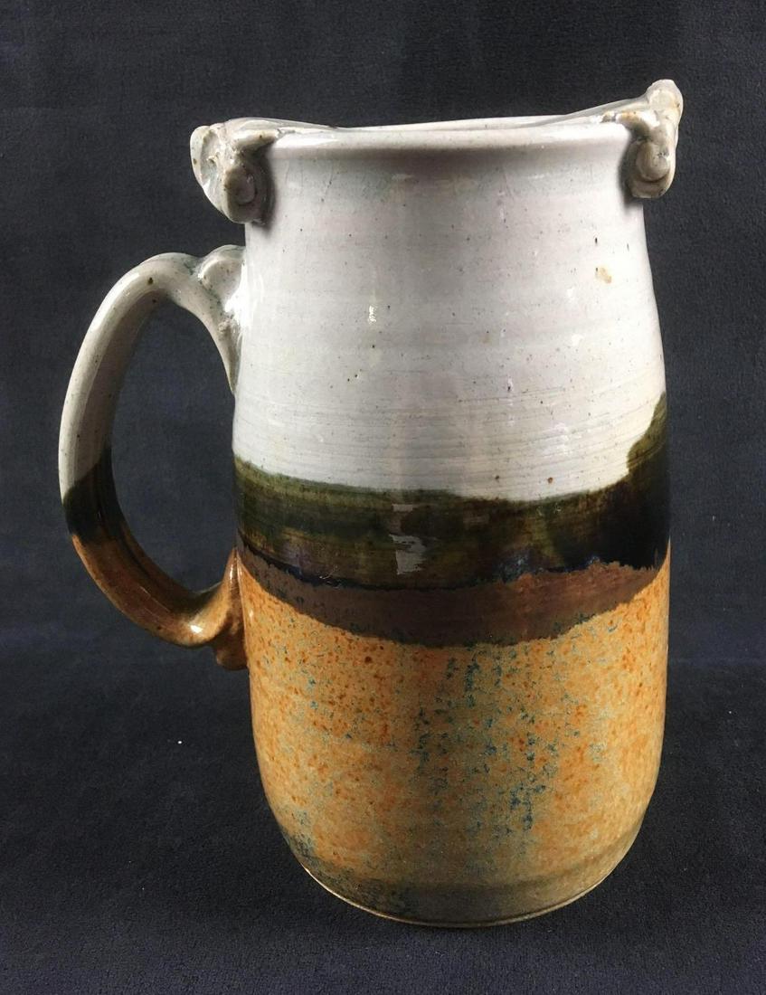 Stoneware Mug: Stoneware Mug. This mug is in good condition. There are no chips or cracks in the ceramic. The mug has an earthen tone glaze. Mug measures 7" H x 4" D at the base.