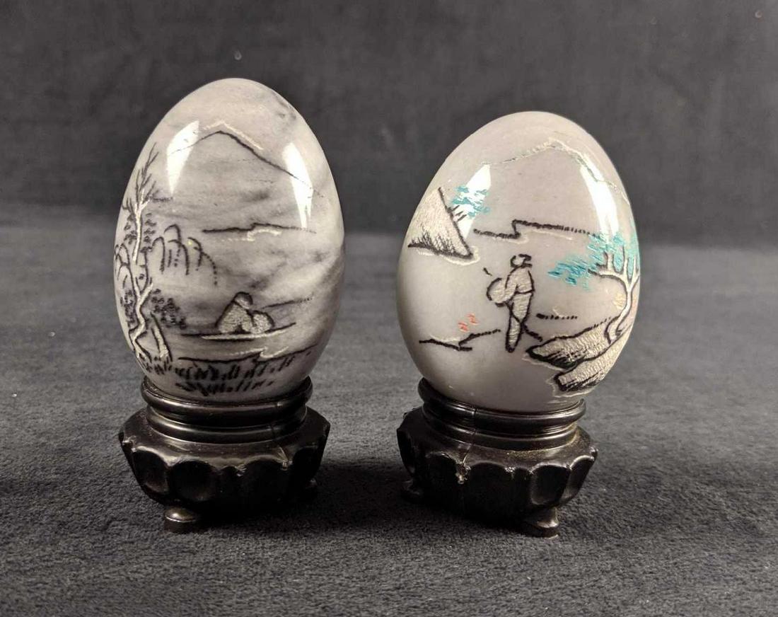 Grey And White Ceramic Chinese Eggs On Stand Set Of Two: Heavy ceramic eggs show calm images of nature and a fisherman. Eggs are in good, used condition with no known chips or scratches. Are approx 2" x 2" x 3". Both come with black, plastic stands.