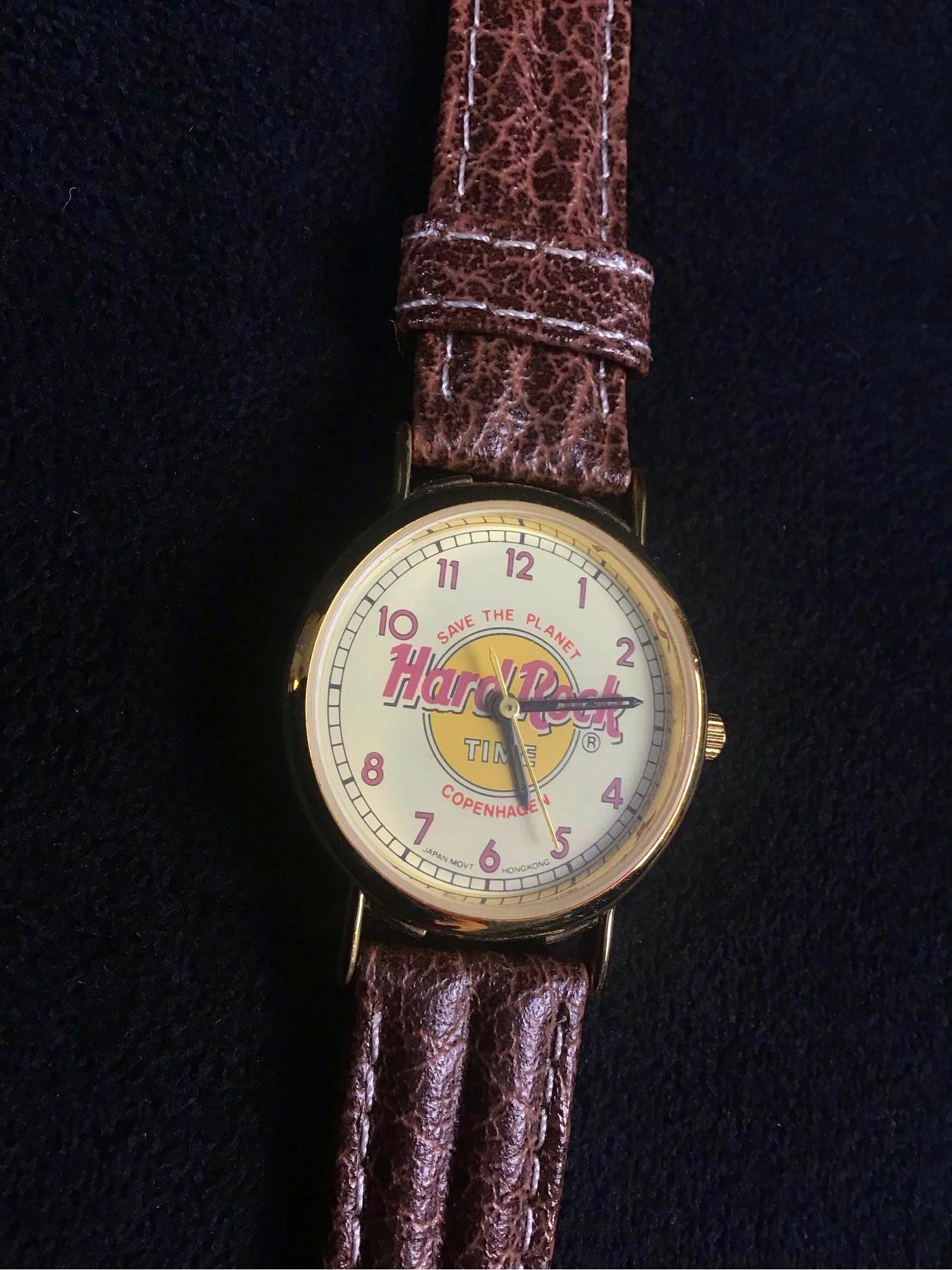 Vintage Hard Rock Cafe Save The Planet Copenhagen: This appears to be a vintage Hard Rock Cafe save the planet watch from Copenhagen. The strap states it is genuine leather. The bezel, crown and clasp are gold colored. The back of the watch says "Stai