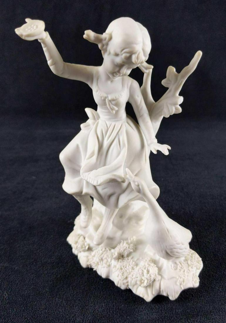 White Ceramic Little Girl With Goose Figurine: White ceramic figurine of a young, pig-tailed girl with a goose. She has food. and the goose wants it! The maker and date of creation are unknown. Figurine is approx 5" x 2 1/2" x 7". The figurine is 