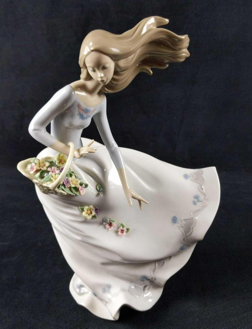 Lladro Petals of The Wind Woman Figurine: Glossy porcelain figurine of a woman's and a basket full of flowers that blows away in the wind and fall down her skirt. Designed by Joan Coderch. Released in 2001. Figurine is approx 11 1/4" x 8". Co
