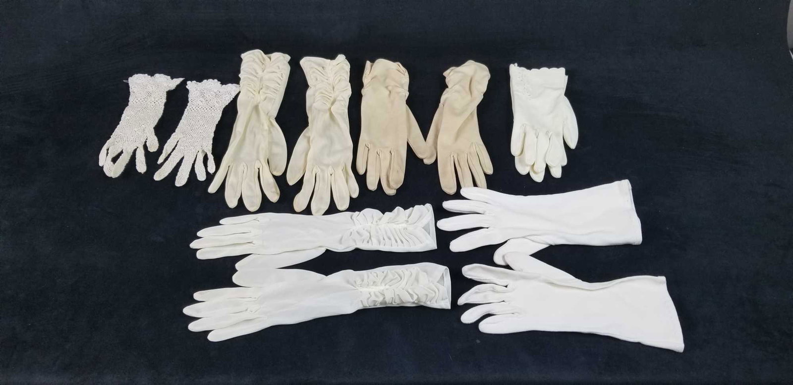 Womens 1950 Style White Hand Gloves: This lot contains 6 pairs of women's white gloves. The date and maker are unknown. In one of the gloves 6 1/2 is stitched on tag. Two pairs are silk and the other are unknown. One set is crochet. Colo