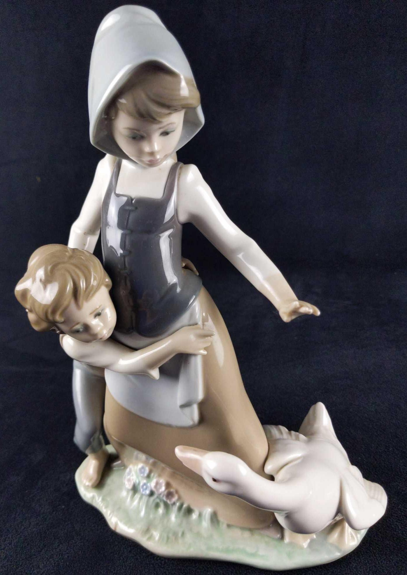 Retired Porcelain Lladro Girl Boy And Goose: Lladro hand made Porcelain "Girl, Boy And Goose" figurine that was designed by Juan Huerta and released from 1979-1994. The figurine is approx 7" x 3" x 10" and is in good, vintage condition with some