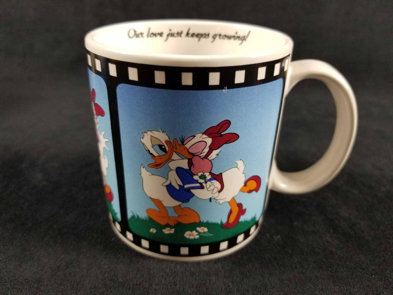1988 Vintage Donald And Daisy Movie Frame Coffe Mug: Applause Walt Disney's Donald Duck and Daisy " Our Love Just Keeps Growing! " coffee mug with a vintage movie frame design. The mug has 3 sequential images of Donald and Daisy . Donald duck picks a fl