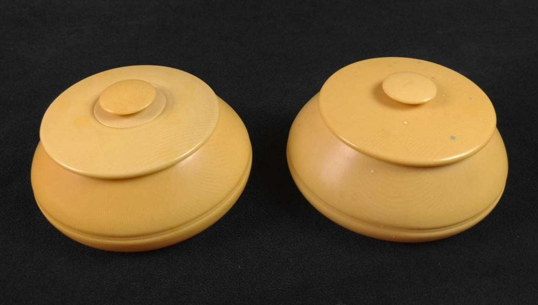 Two Small Bakelite Ivory Colored Containers Vanity: This lot contains two small Bakelite Ivory Colored Containers. One has some buttons inside. Both containers are approx 5" x 5" x 3" and are in a good, vintage condition with some wear, markings, and s