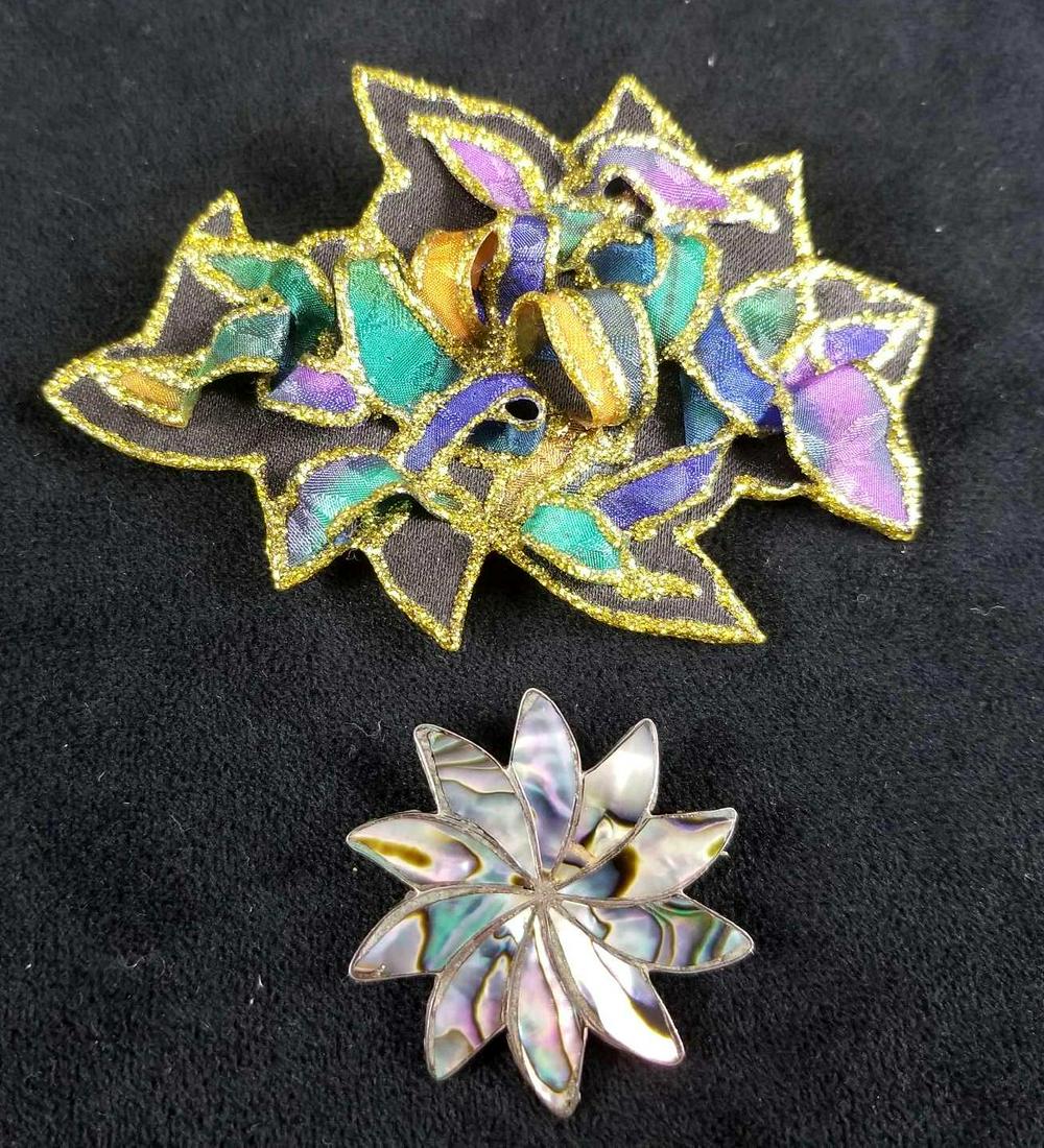 Lot of 2 Flower Brooches from the 80s: This lot of vintage brooches features a fabric brooch from the 80's era that depicts texture and painted purple, green, and royal blue with gold glitter toned edges; in very good used condition with n