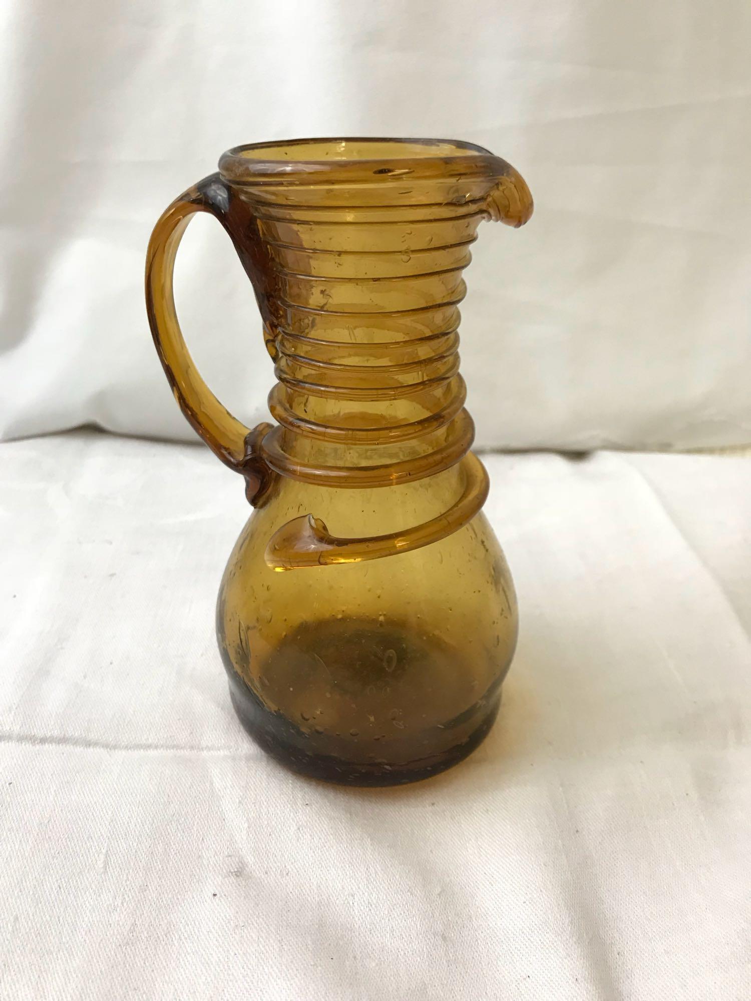 Handmade Vintage Israeli Amber Glass Carafe: Handmade Vintage Israeli Amber Glass Carafe; Hand-blown amber bubbled glass carafe with applied spiral on neck. It measures at approximately 6" H x 3" D.