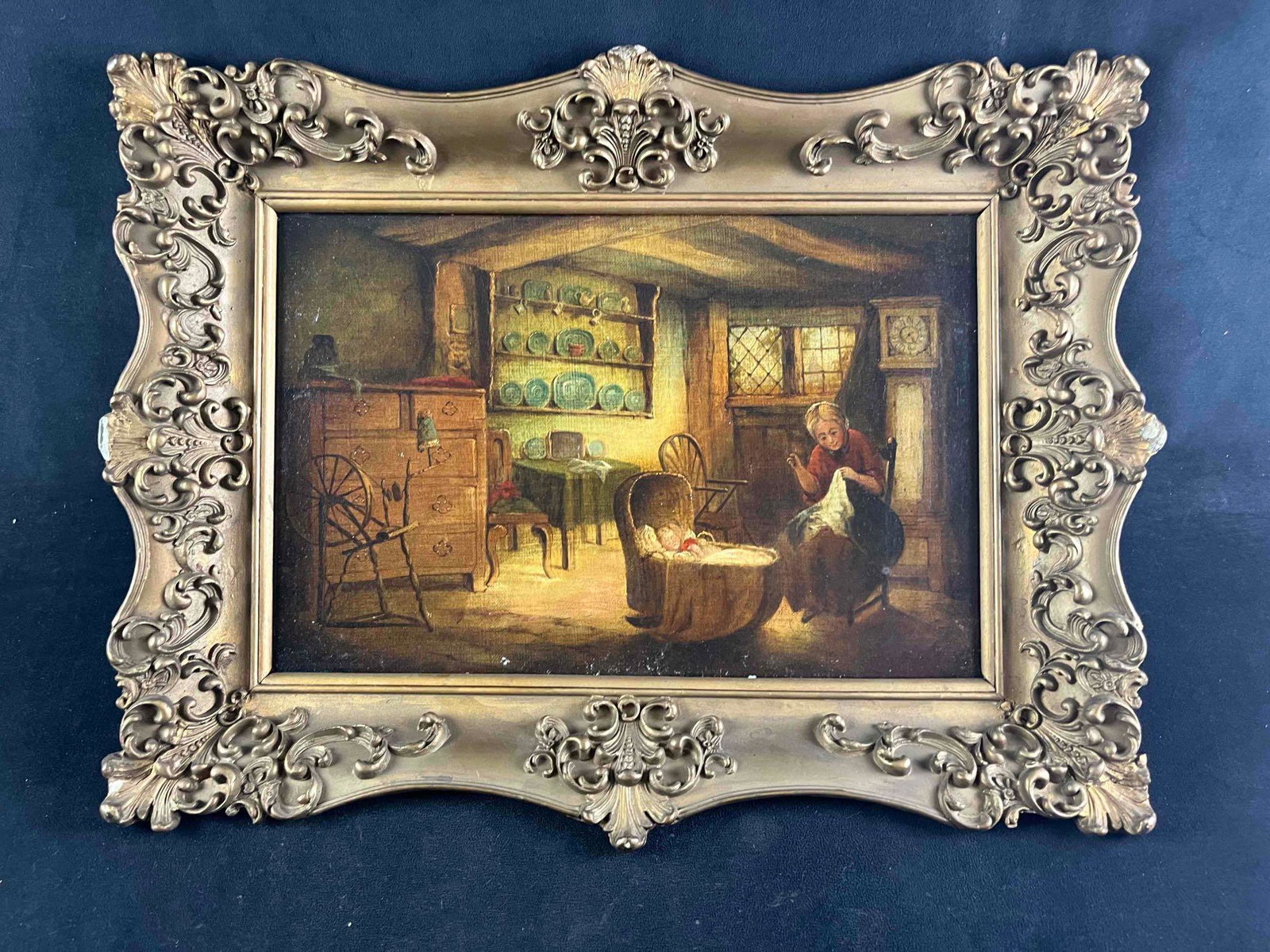 Antique Framed Oil Painting With Glossy Varnish: Antique Framed Oil Painting With Glossy Varnish This painting is of a mother sewing while watching her baby in a bassinet. The background is inside a farmhouse with old furniture and a yarn wool spinn