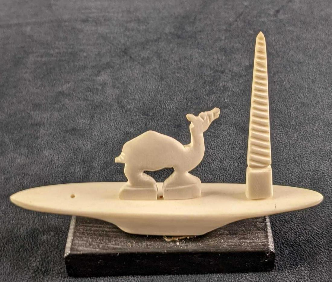 Natural Carved Bone Egyptian Camel Figurine: Natural Carved Bone Egyptian Figurine On A Wood Base. Appears to be camel bone and of a camel who has stopped to admire an obelisk. The maker or date of creation is unknown. Is approx 6 1/4" x 1 1/2" 