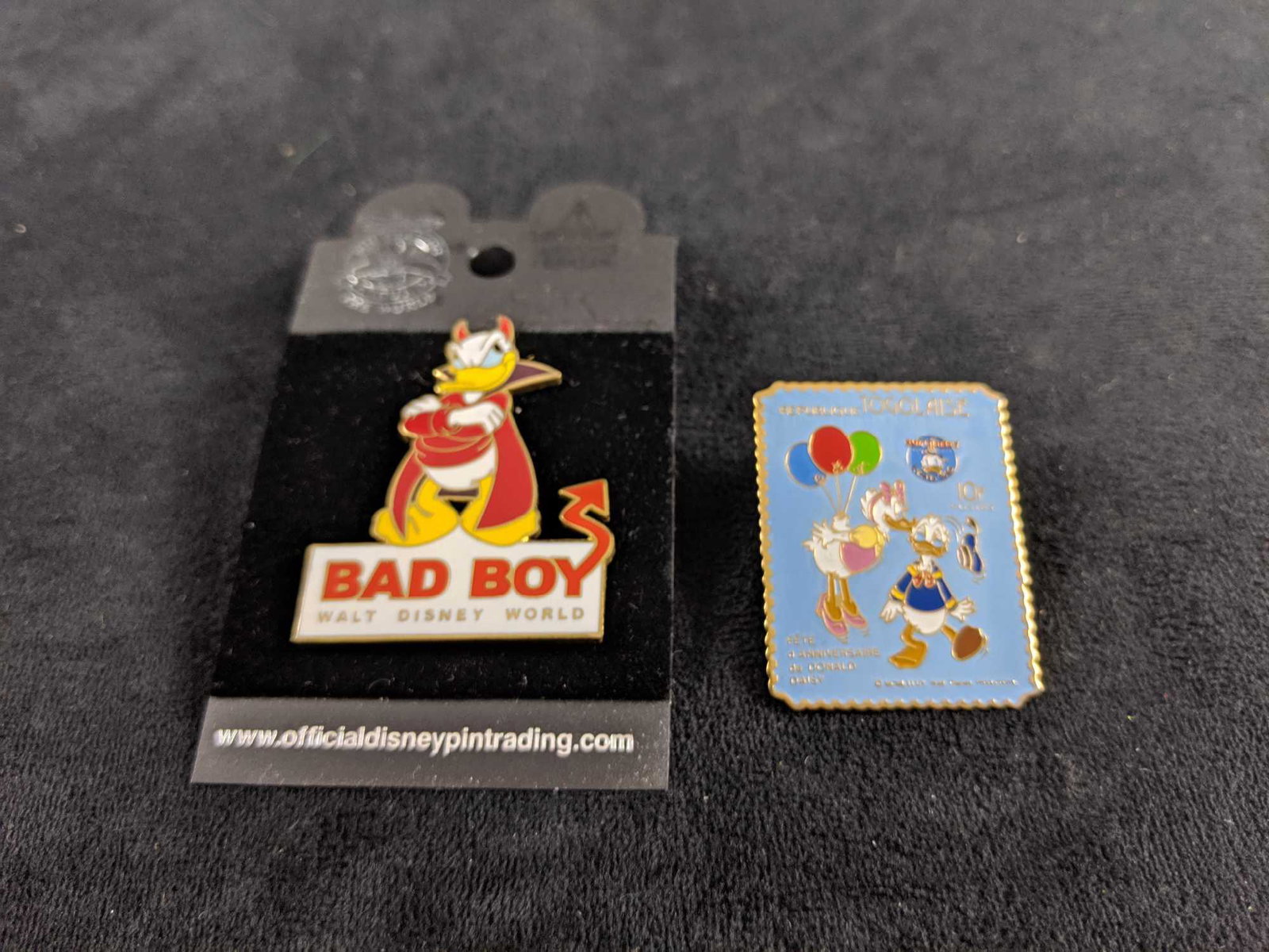 Lot Of Two Disney Sweet Or Sour Donald Duck Pins: This lot consists of one "Bad Boy" Donald Duck pin with backing and one Donald & Daisy "Republique Togolaise Stamp" pin. These pins are in good, used condition with no visible markings or scratches. P