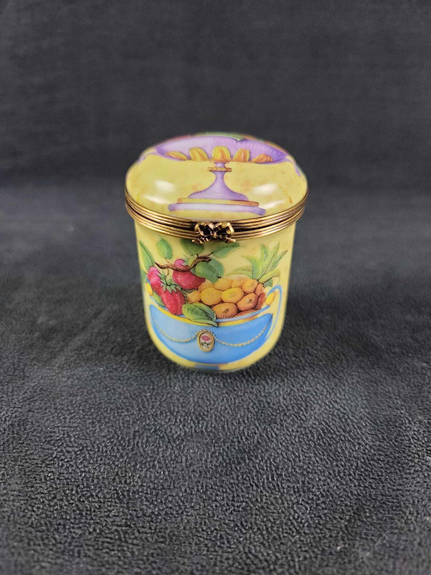 Floral French Limoges Trinket Box: This trinket box is made of porcelain and made in France. The maker is unknown. There is a snap closure with a detailed bow at the closure. There is an ornate floral design on the outside. It is stamp