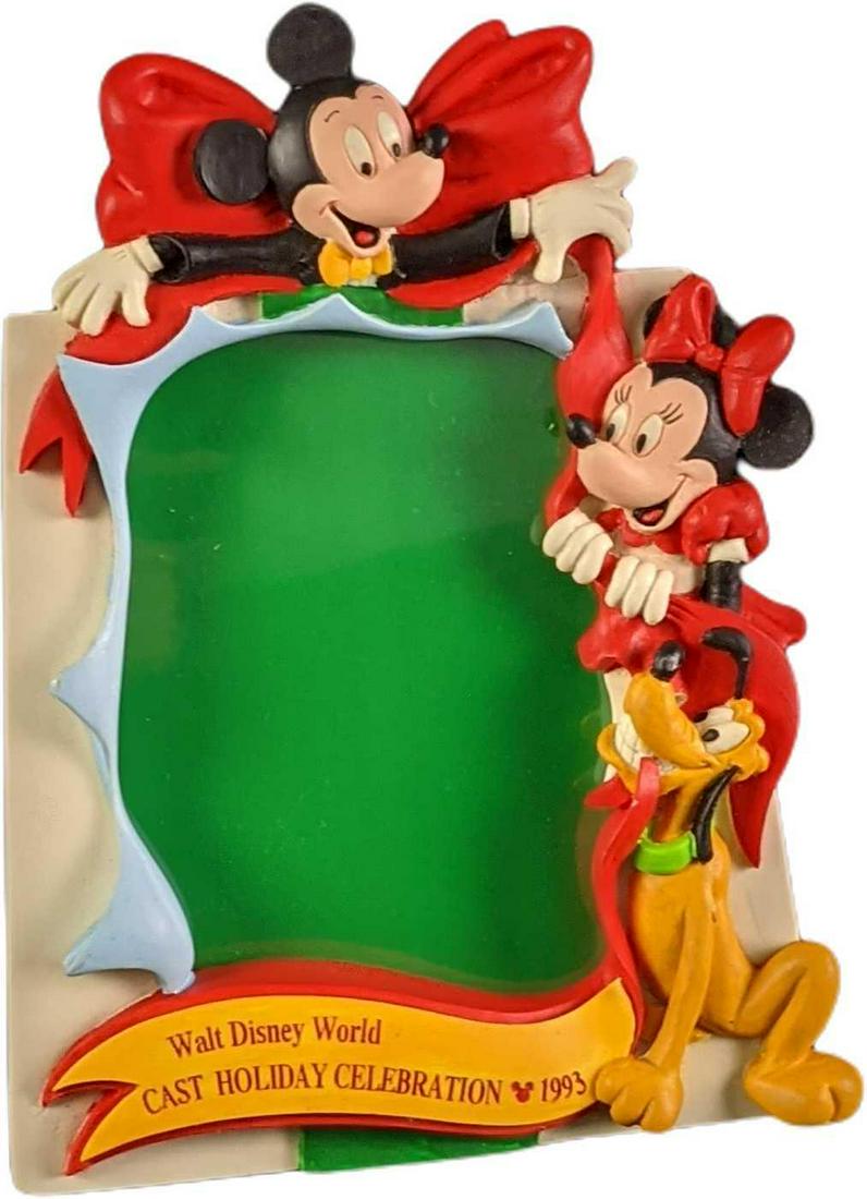 Disney World Cast Exclusive Celebration Photo Frame: 1993 Walt Disney World Cast Holiday Celebration 1993 Resin Picture Frame. Cast exclusive, Frame has Mickey Mouse, Minnie Mouse, and Pluto who are in the process of tying a big bow on the frame. Can be