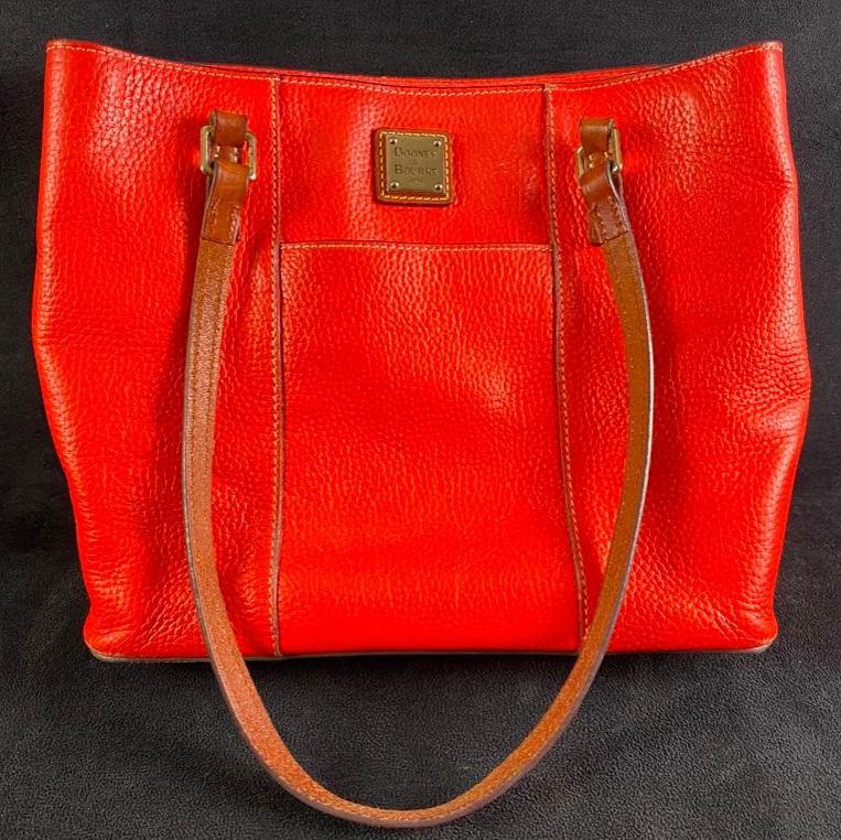Dooney & Bourke Lexington Shopper Leather Bag: Dooney & Bourke Lexington Shopper Leather Bag Orange leather Lexington Shopper handbag by Dooney & Bourke. Features tan leather handles and two small outside pockets. The bag has some wear on the leat