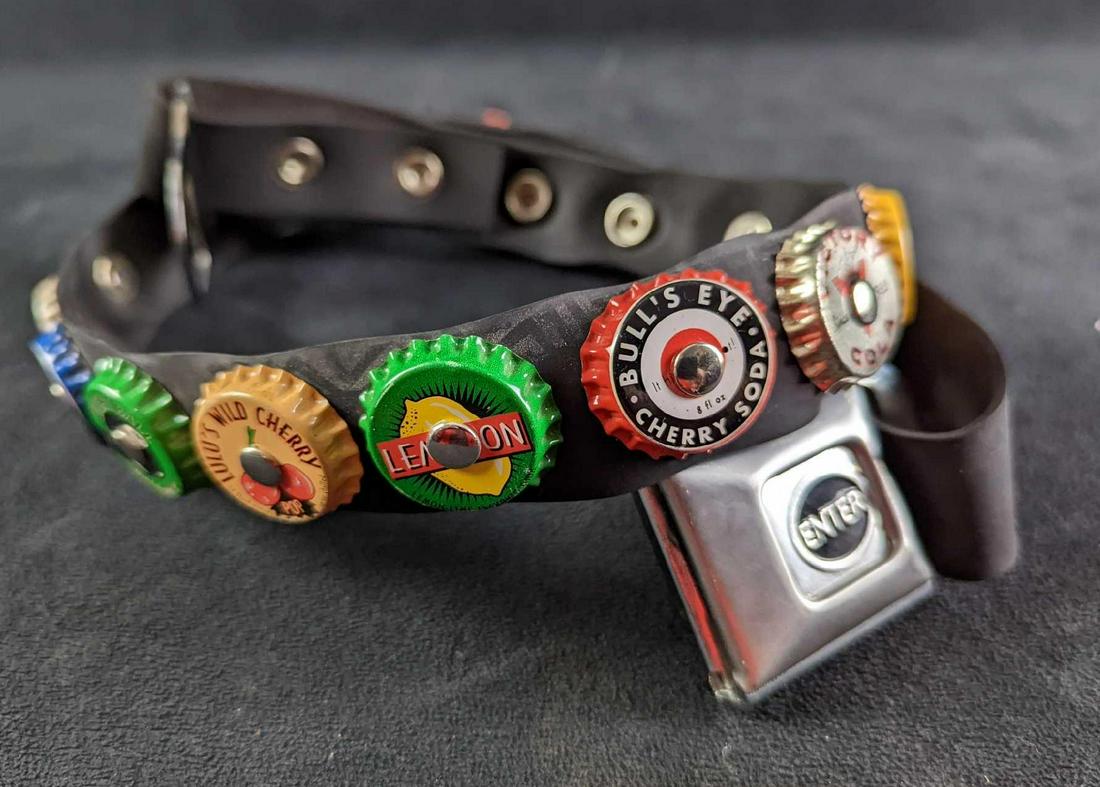 Little Earth Rubber Bottle Cap Belt: Little Earth Rubber Bottle Cap Belt. The belt is 37" long and the end also works as a bottle opener. The belt is in a good, unused condition with some light tarnish on the metal. The total weight is 0