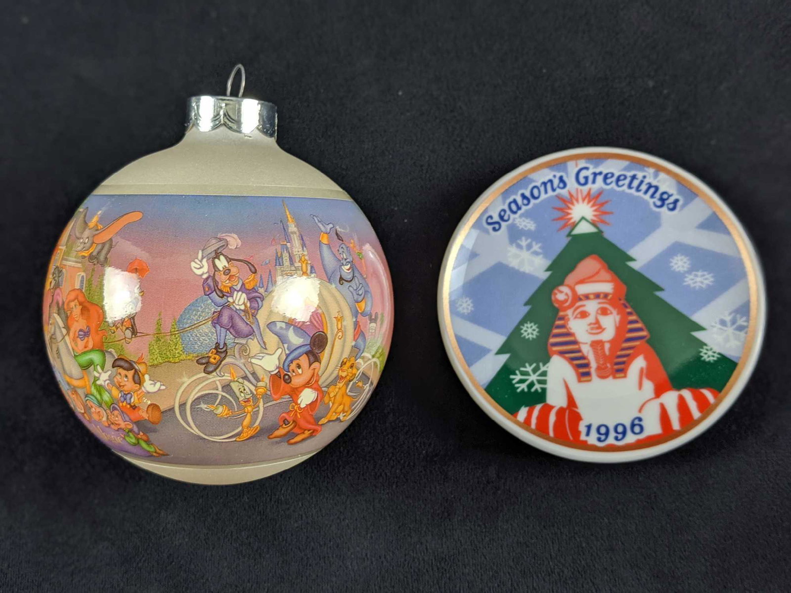 Disney 25th Anniversary And Sphinx Ornament Lot: This lot includes one Walt Disney World 25th Anniversary Glass Ball Christmas Ornament. This measures approx 3" x 3" x 4". And one 1996 World Wine Line porcelain Sphinx mini-plate ornament. This measu