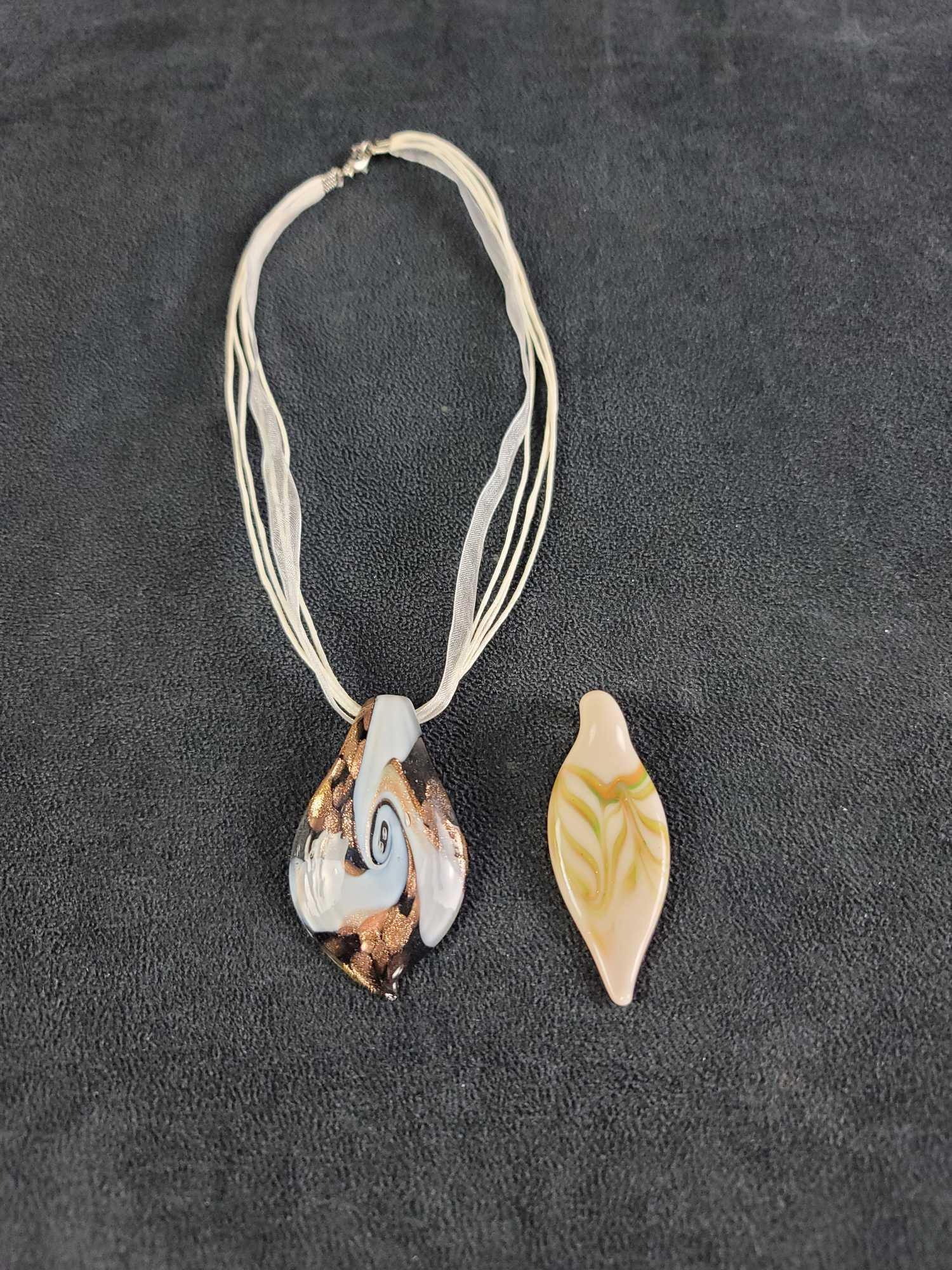 Glass Leaf Pendants with Choker Necklace: This lot contains: 2 glass leaf pendants with various color patterns and comes with a white cord with white ribbon choker necklace. Necklace has a safety clasp. Maker is unknown. In good condition. Ap