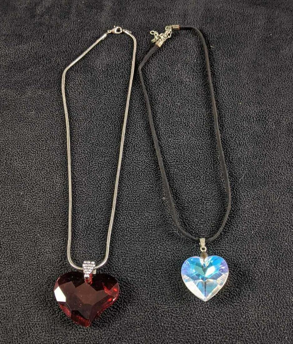 Glass Heart Necklaces: Glass Heart Necklaces This lot has two necklaces with glass heart pendants. One is on a silver-colored chain and the other is on a cloth chain. These necklaces are in good condition with slight wear.
